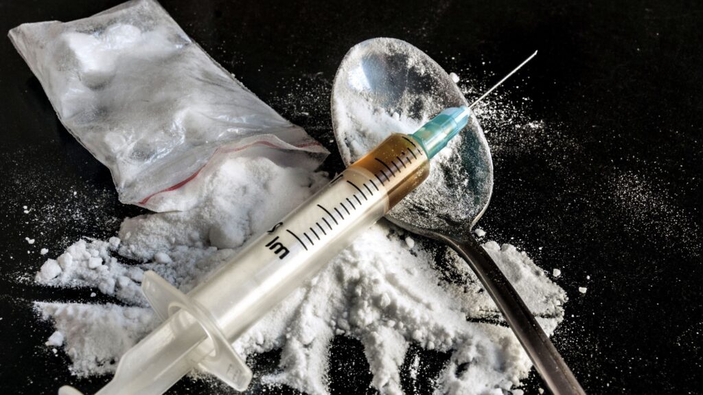 Drug syringe and cooked heroin on spoon