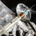 Drug syringe and cooked heroin on spoon